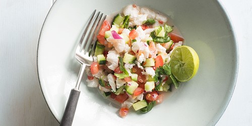 freshly made Ceviche with sealord frozen fish fillets, garnished with lime, served on a whit bowl with a fork laying next to the ceviche.
