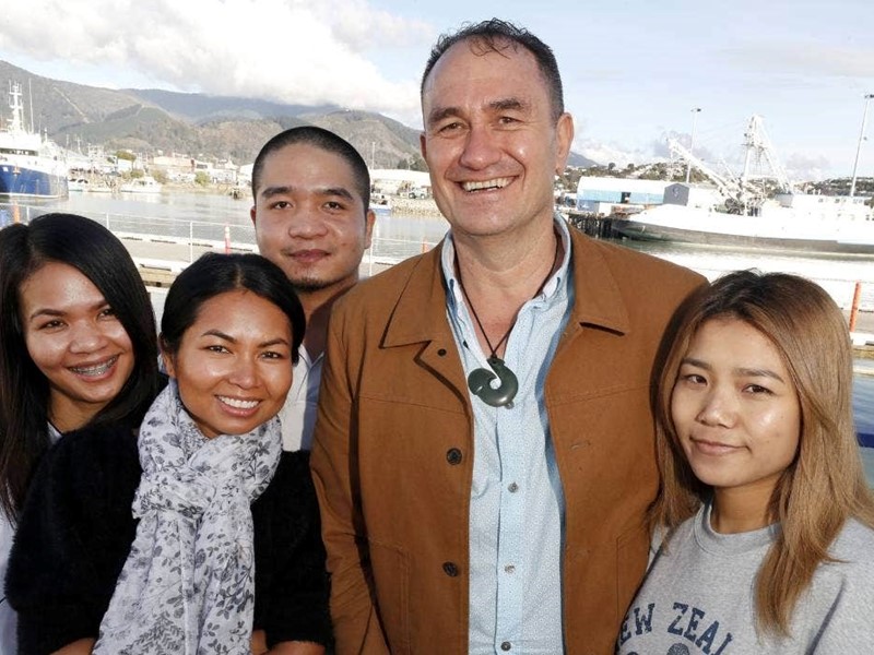 sealords ceo and workers huddleded together for a photo standing infront of the port, blue skies in NZ