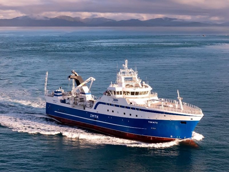 seaord fishing boat underway in the open ocean, Mountains in the distant background paired with a calm sea in NZ