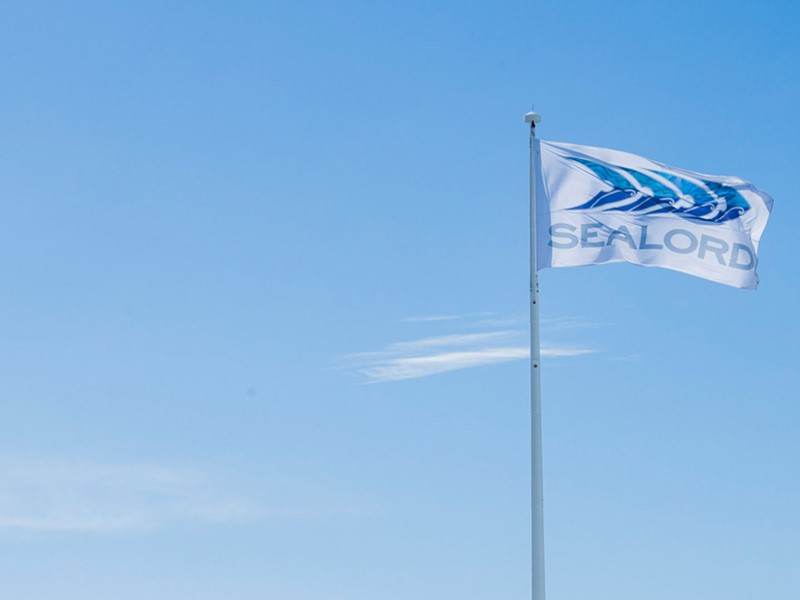 Sealord flag flying against a clear blue sky, showcasing the company’s logo in white and blue.