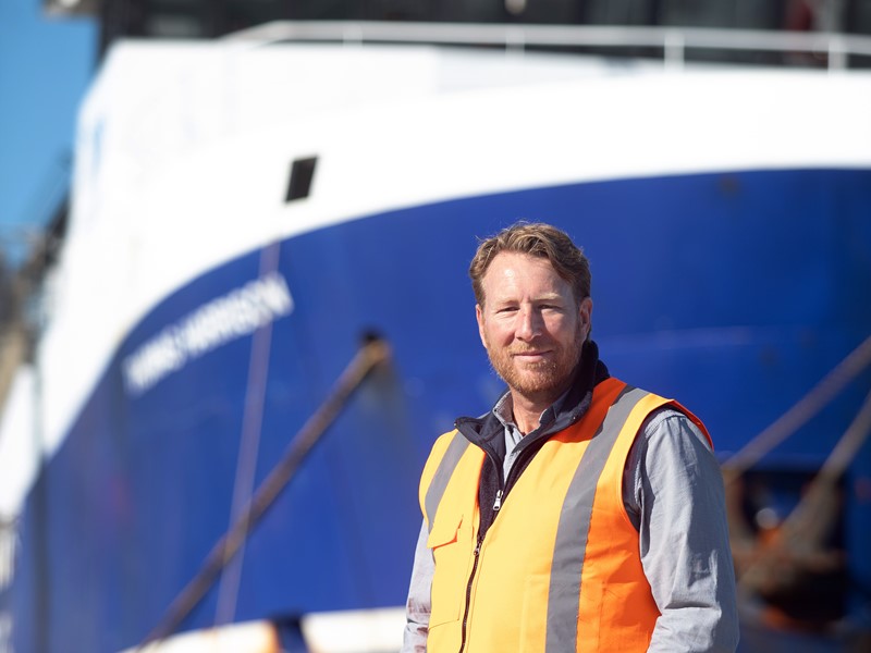 sealord employee standing in visibility gear in front of sealord blue an white vessel boat, introducing new measures to reduce seal capture