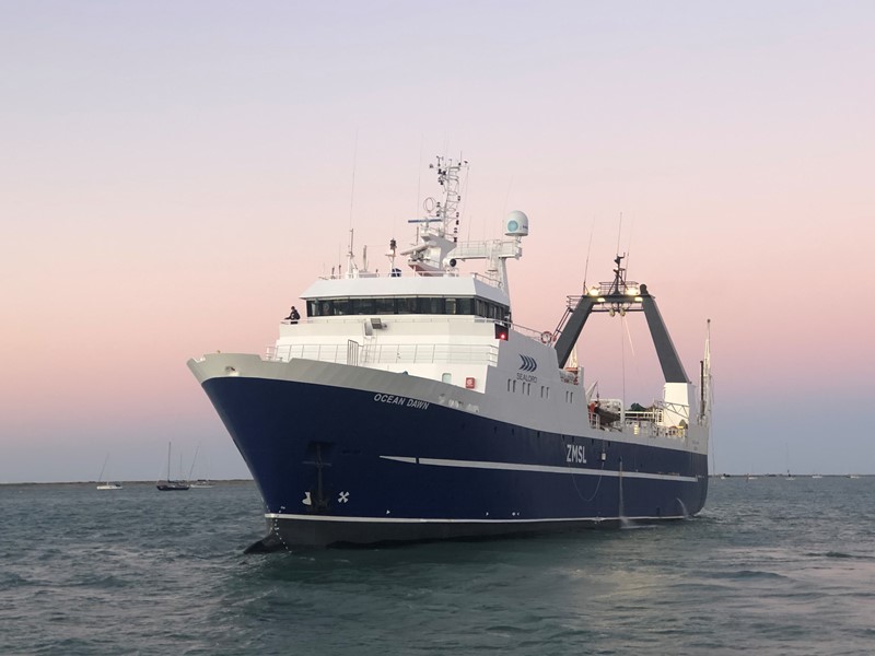 Sealord fishing vessel Ocean Dawn at sea, front view with a pink and purple sunset sky on the horizon.
