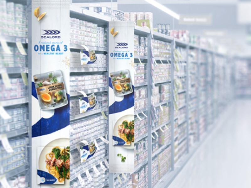 Supermarket aisle featuring Sealord Omega 3 seafood product displays with promotional banners and shelves stocked with canned goods.