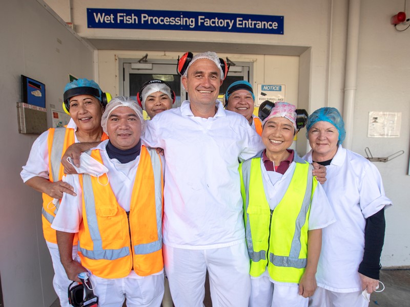 group of factory sealord staff huddled around for a photo n their hair nets, high vis uniform