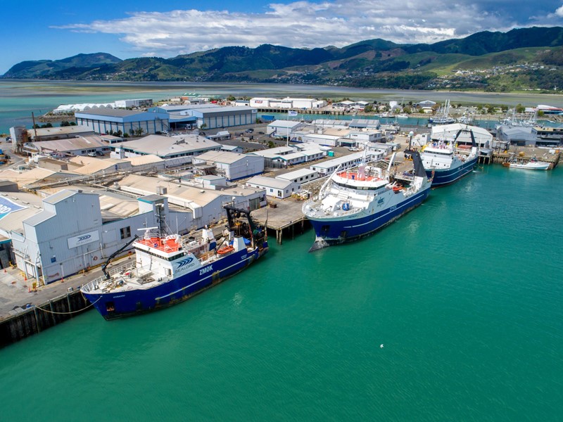 Three Sealord fishing boats lined up at the dock with mountains rising in the background